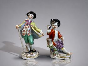 TWO MEISSEN PORCELAIN FIGURINES. The first depicting a young boy seated on a stump with a bunch of