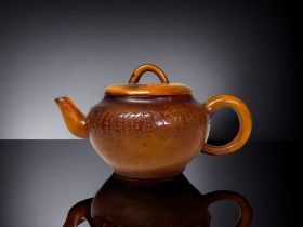 A CHINESE CARVED AMBER TEAPOT. Qing dynasty. Carved Tokens with script to body and lid. Impressed