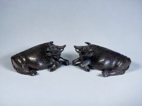 A PAIR OF CHINESE CARVED HARDWOOD BUFFALO. Circa 1900. Inlaid with silver patterns and ceramic eyes.