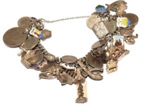 Large charm bracelet with multiple charms many silver coins and a fairy with a safety chain 102g