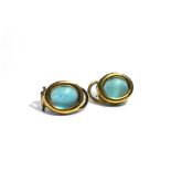 A pair of yellow metal & blue cabochon stone set earrings. 