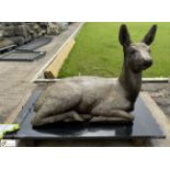 A reconstituted stone seated Deer, on black marble plinth, approx. 20in x 17in x 31in