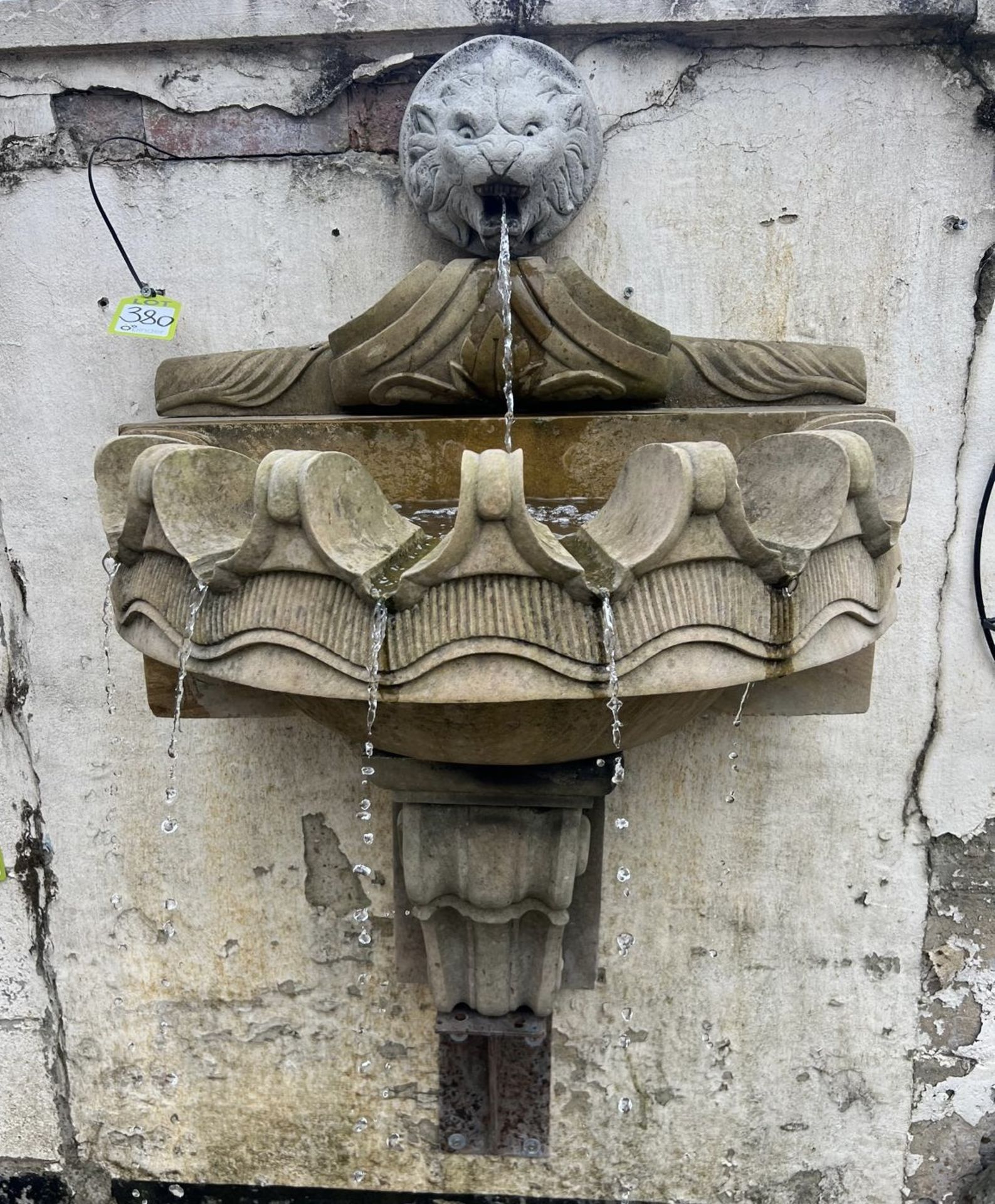 A Wall Fountain comprising reconstituted stone lions head waterspout, mounted above a sandstone clam