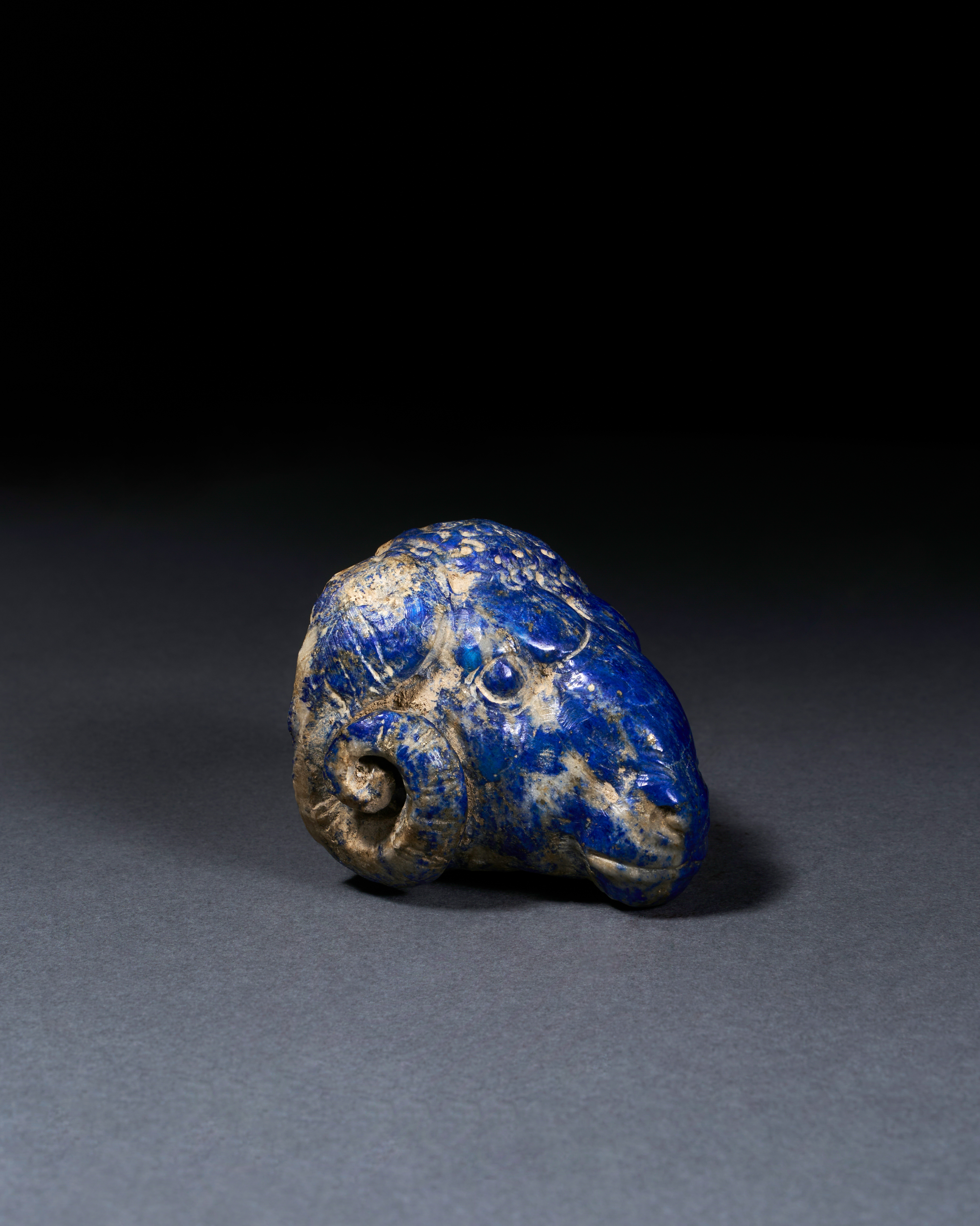 A RARE ACHAEMENID LAPIS LAZULI "RAM" HEAD STAFF ATTACHMENT, CIRCA 6TH CENTURY B.C.