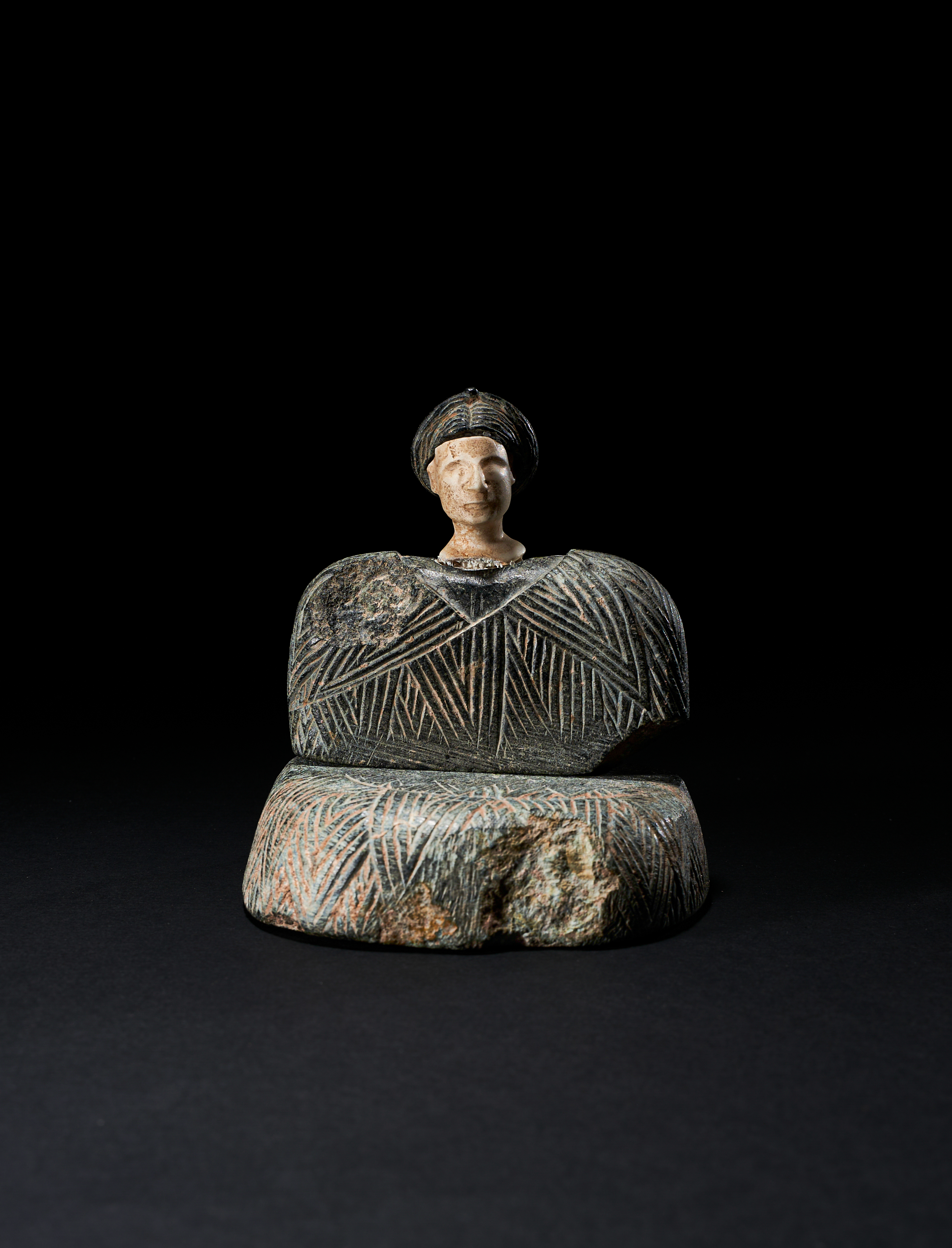 A BACTRIAN CHLORITE AND LIMESTONE SEATED FEMALE FIGURE CIRCA LATE 3RD-EARLY 2ND MILLENNIUM B.C.