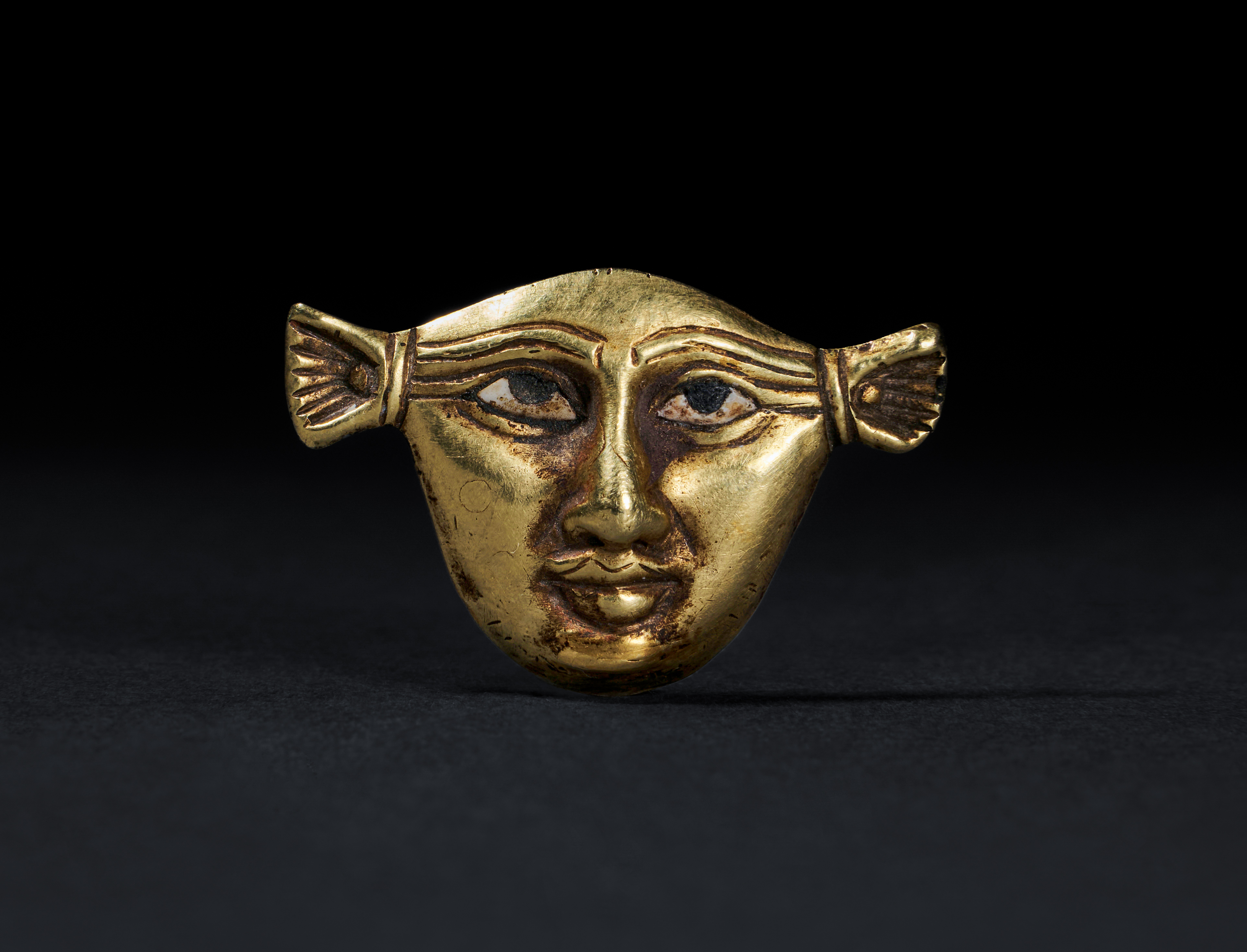 AN EGYPTIAN GOLD FACE INLAY, NEW KINGDOM, AMARNA PERIOD, DYNASTY XVIII, CIRCA 1353-1336 B.C.