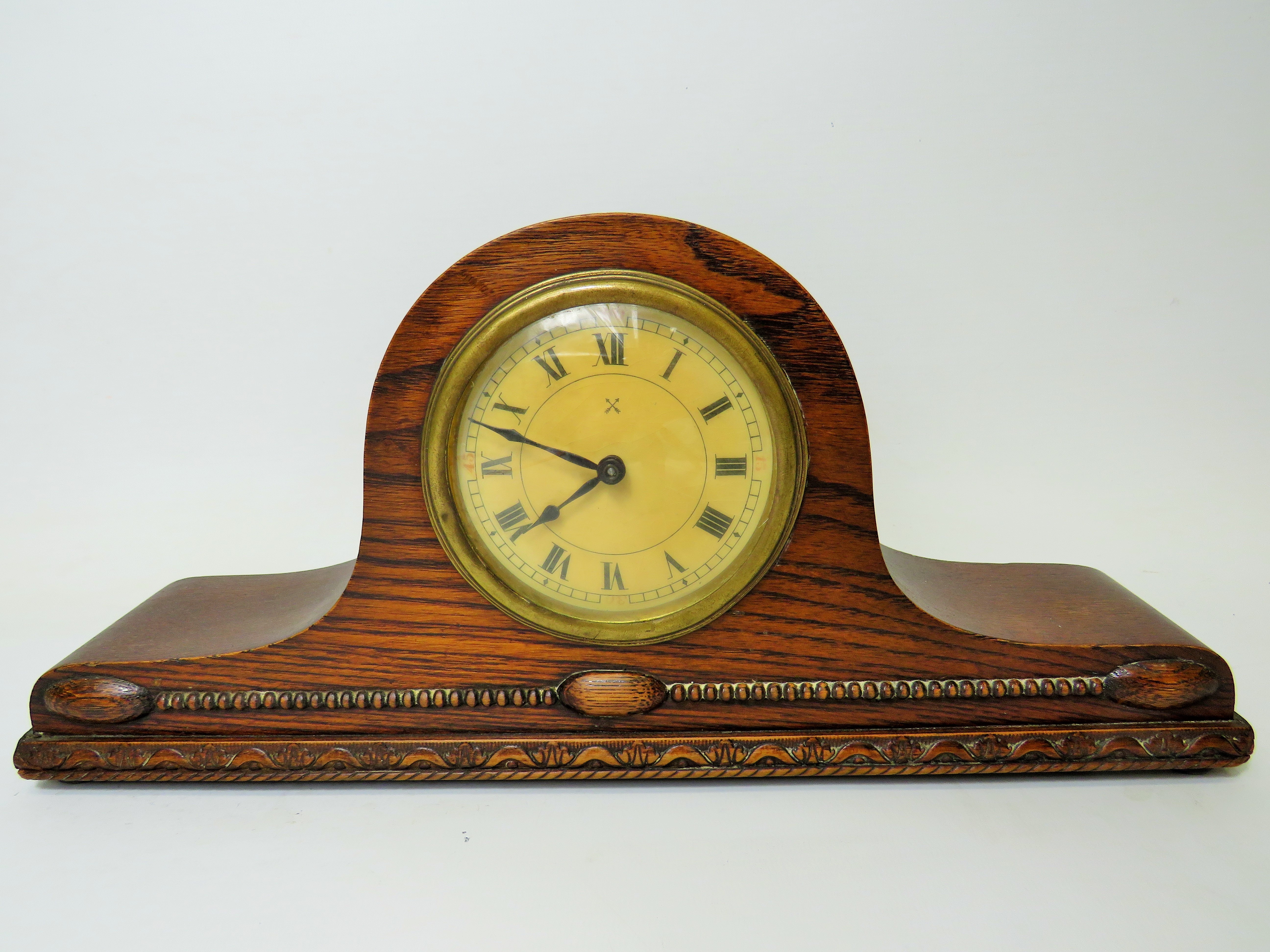 Oak cased mantle clock with ornate carving to the base. Brass mechanism in running order. Measures 1