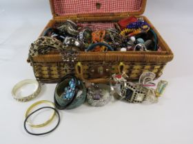 Wicker basket containing a large quantity of costume jewellery bracelets.