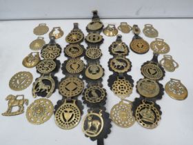 35 vintage horse brasses some with leathers.