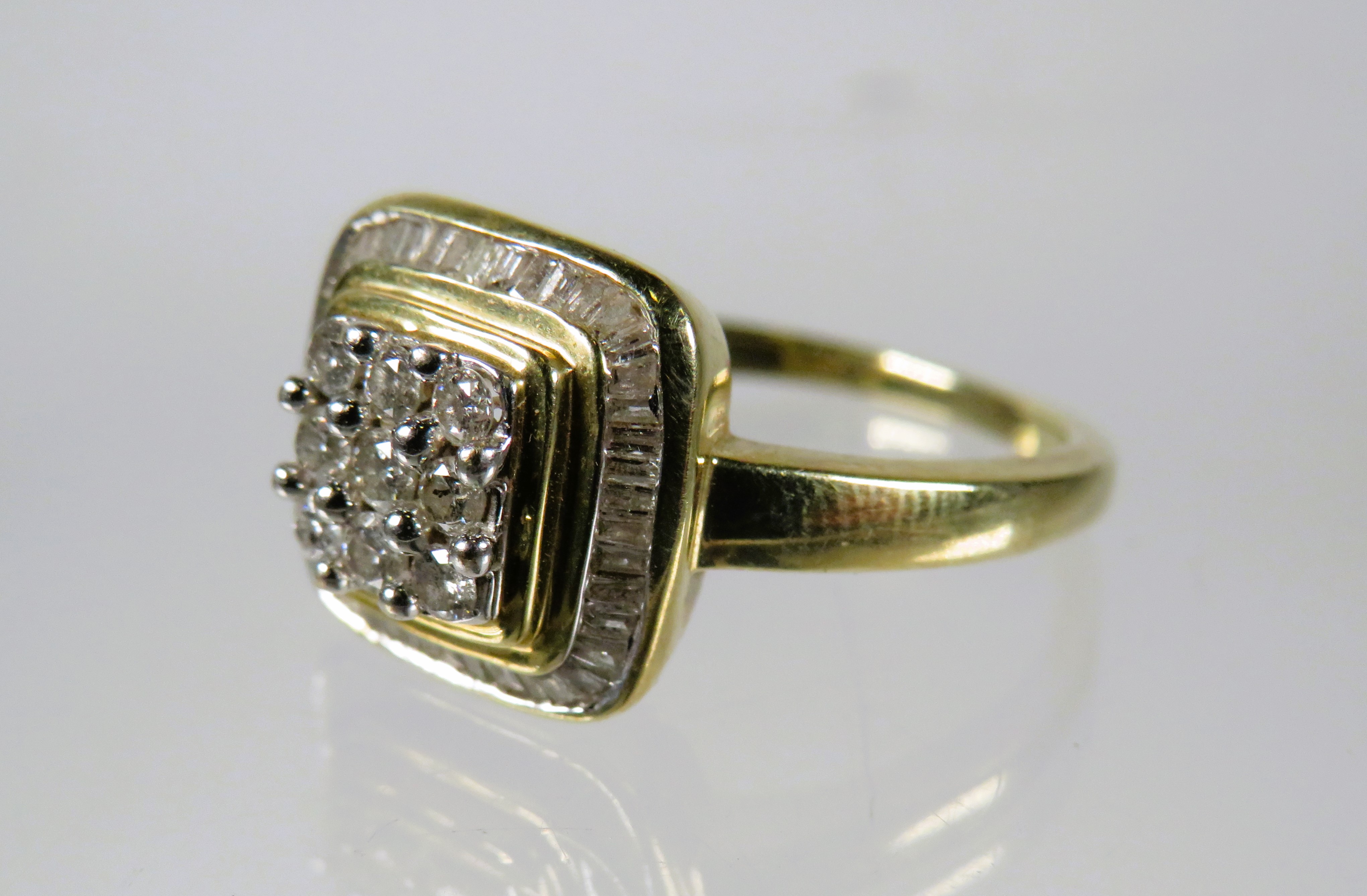 9ct Yellow Gold Ring set in an Art Deco style and set with nine circular Diamonds with Diamond Surro