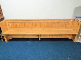 Long and well constructed pine pew with fitted plate rack to rear. H:33 x W:107 x D:20 Inches.