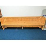 Long and well constructed pine pew with fitted plate rack to rear. H:33 x W:107 x D:20 Inches.