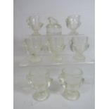 Seven glass chick egg cups and a lidded trinket.