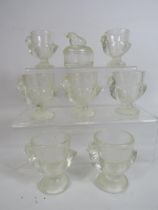 Seven glass chick egg cups and a lidded trinket.