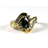 9ct Yellow Gold ring set with an Oval Central Sapphire, Multiple Diamond surround in a wave pattern.