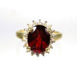 9ct Yellow Gold ring set with a large Oval Garnet which measures approx 10 x 8 mm with Diamond Surro