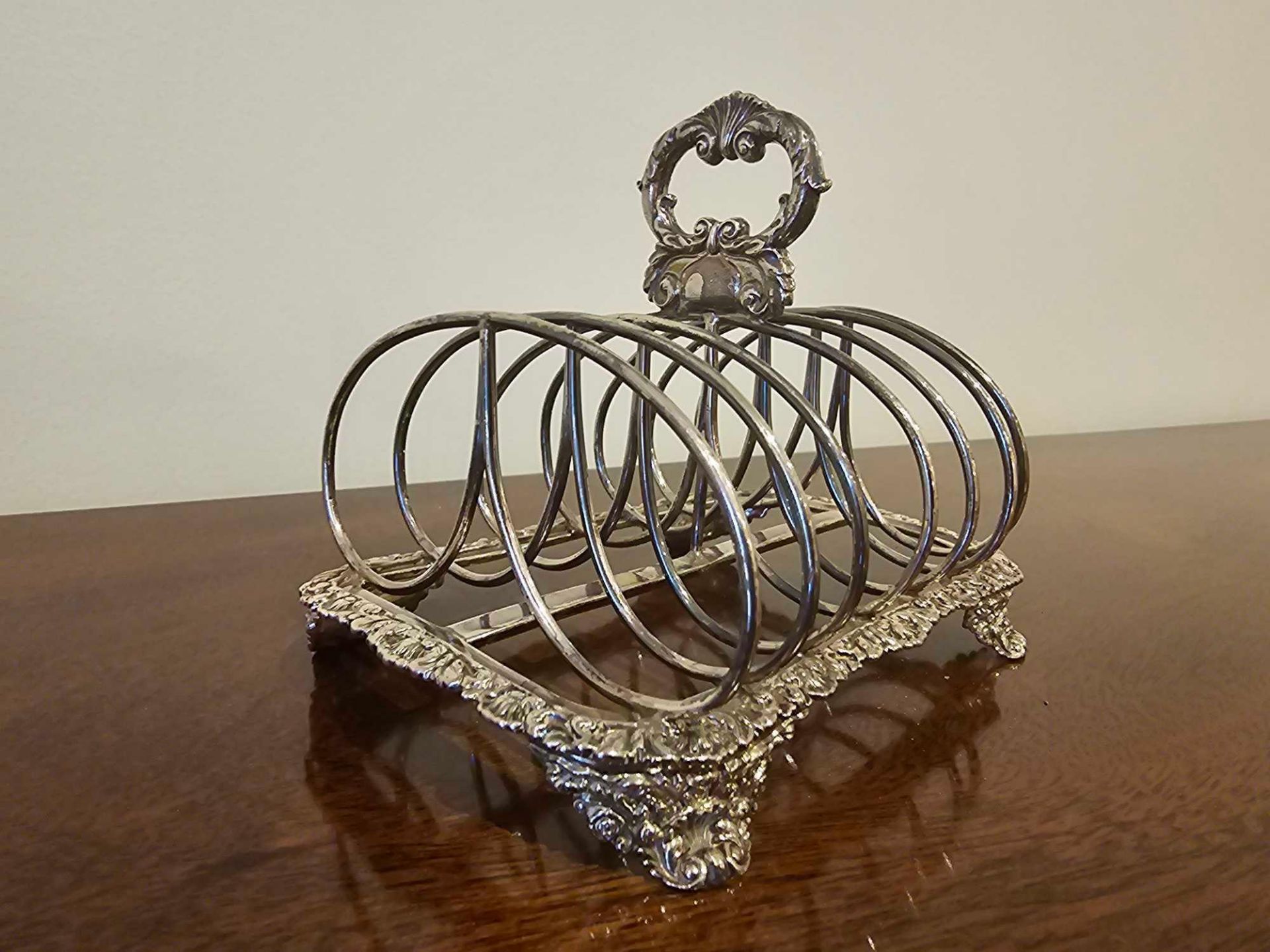 A George IV Style Silver Toast Rack 7 Bar With Rocaille Oval Handle And Border On Similar Bracket