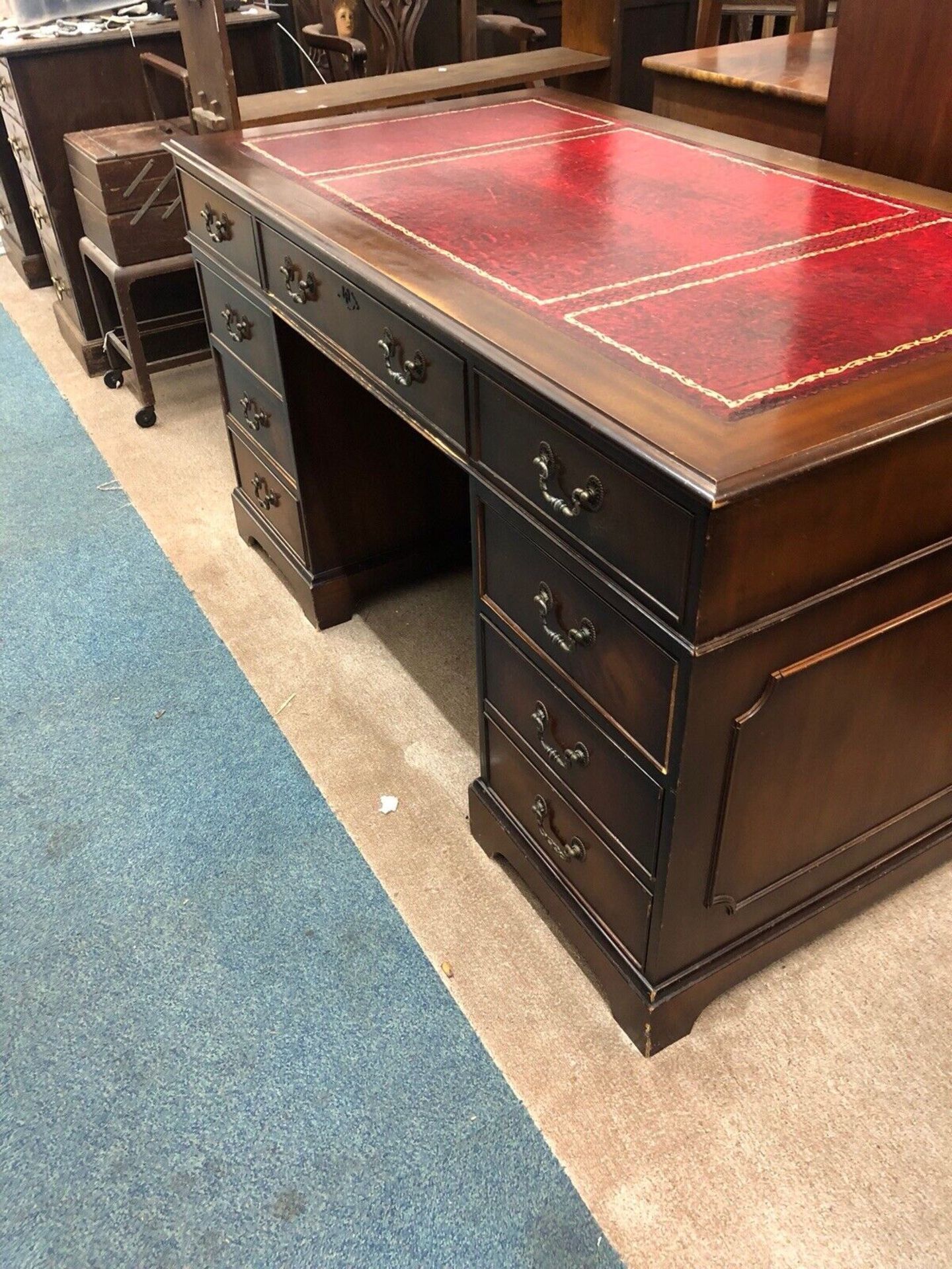 George III style mahogany pedestal desk. The rectangular top with a red leather and tooled insert,