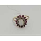 AN OPAL OVAL CLUSTER RING WITH DIAMOND & RUBY BORDER IN GOLD,