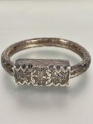 A Eastern white metal chased sleeve bangle of large size with rectangular panel, (D x 10 cm)