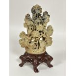 A large Chinese soap stone carved chrysanthemum and bird panel raised on oval dark brown soap