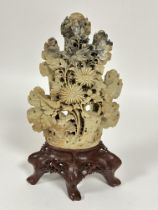 A large Chinese soap stone carved chrysanthemum and bird panel raised on oval dark brown soap