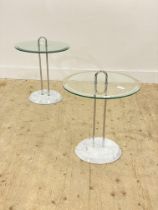 A pair of modern circular glass topped occasional tables raised on twin chrome supports and marble