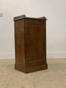 A walnut pedestal bedside cabinet, with galleried top above a panelled door enclosing a shelf,