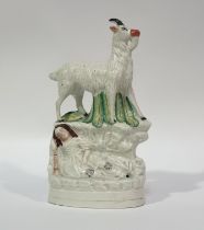 A 19thc Staffordshire porcelain figurine of a goat with a sleeping girl below, decorated with
