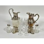 A pair of glass individual custard jugs with Birmingham silver tops, one loose, (H x 10 cm), a