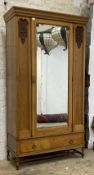 An early 20th century Art Nouveau style oak wardrobe, the the bevel glazed mirror door flanked by