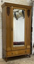 An early 20th century Art Nouveau style oak wardrobe, the the bevel glazed mirror door flanked by