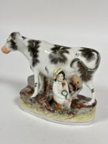 A 19thc Staffordshire china flatback group milking time with seated farmer decorated with polychrome