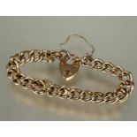 A 9ct gold curb link bracelet with 9ct gold heart shaped padlock and safety chain, (D x 8 cm) 15.4