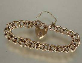 A 9ct gold curb link bracelet with 9ct gold heart shaped padlock and safety chain, (D x 8 cm) 15.4