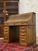 An early 20th century oak serpentine roll top desk, the tambour front opening to reveal a fitted