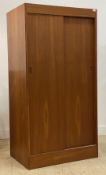 A mid century teak wardrobe, the twin sliding doors enclosing an interior fitted with shelves and