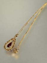 An 18ct gold oval openwork pendant necklace set red pear shaped stone in four claw setting on 18ct