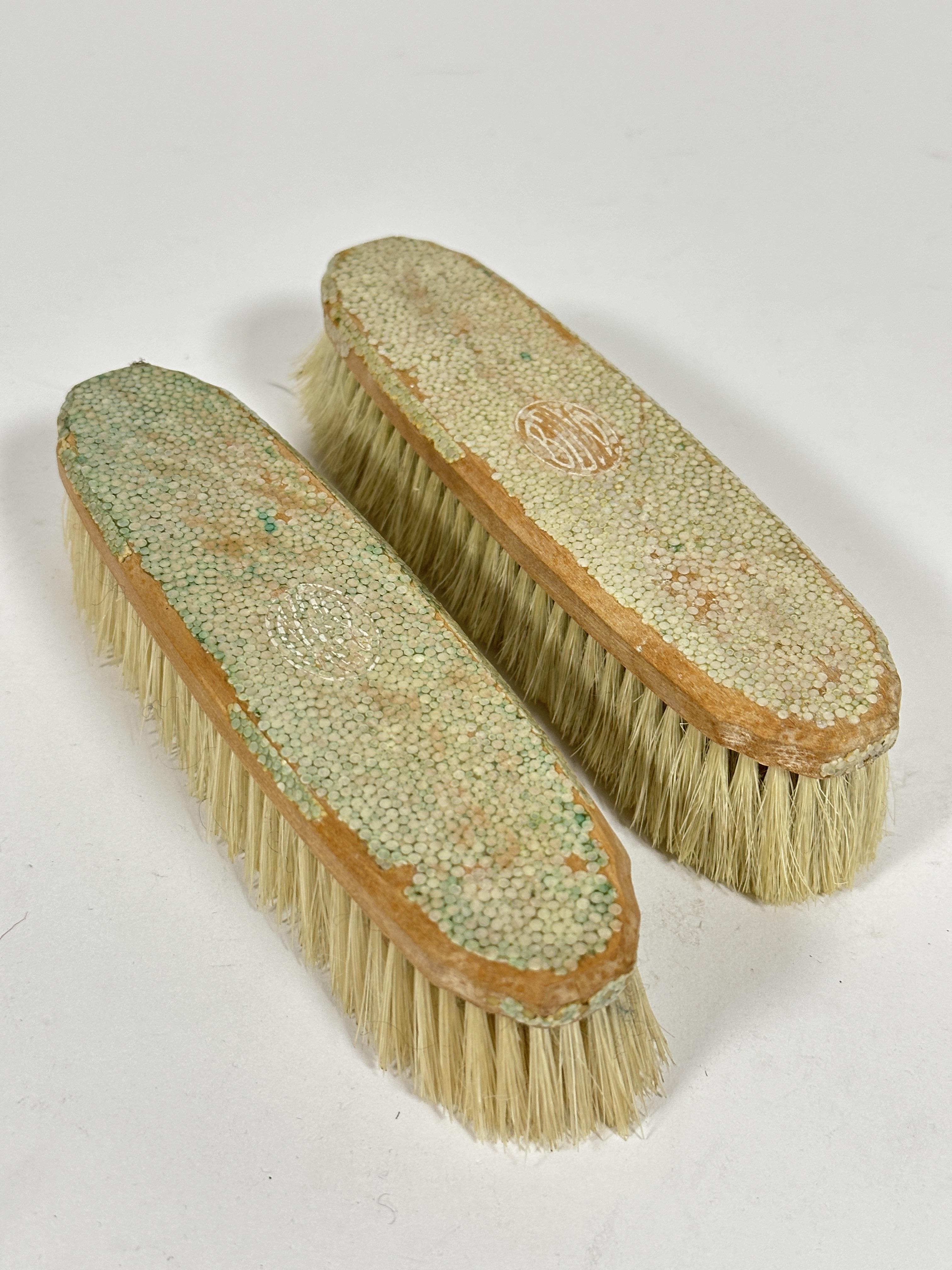 A 1930s shagreen pair of clothes brushes, losses to surfaces of both. (L x 17 cm)