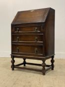 An early 20th century oak bureau, the fall front revealing a fitted interior, above three drawers,