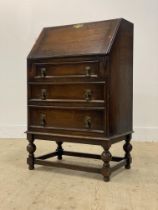 An early 20th century oak bureau, the fall front revealing a fitted interior, above three drawers,