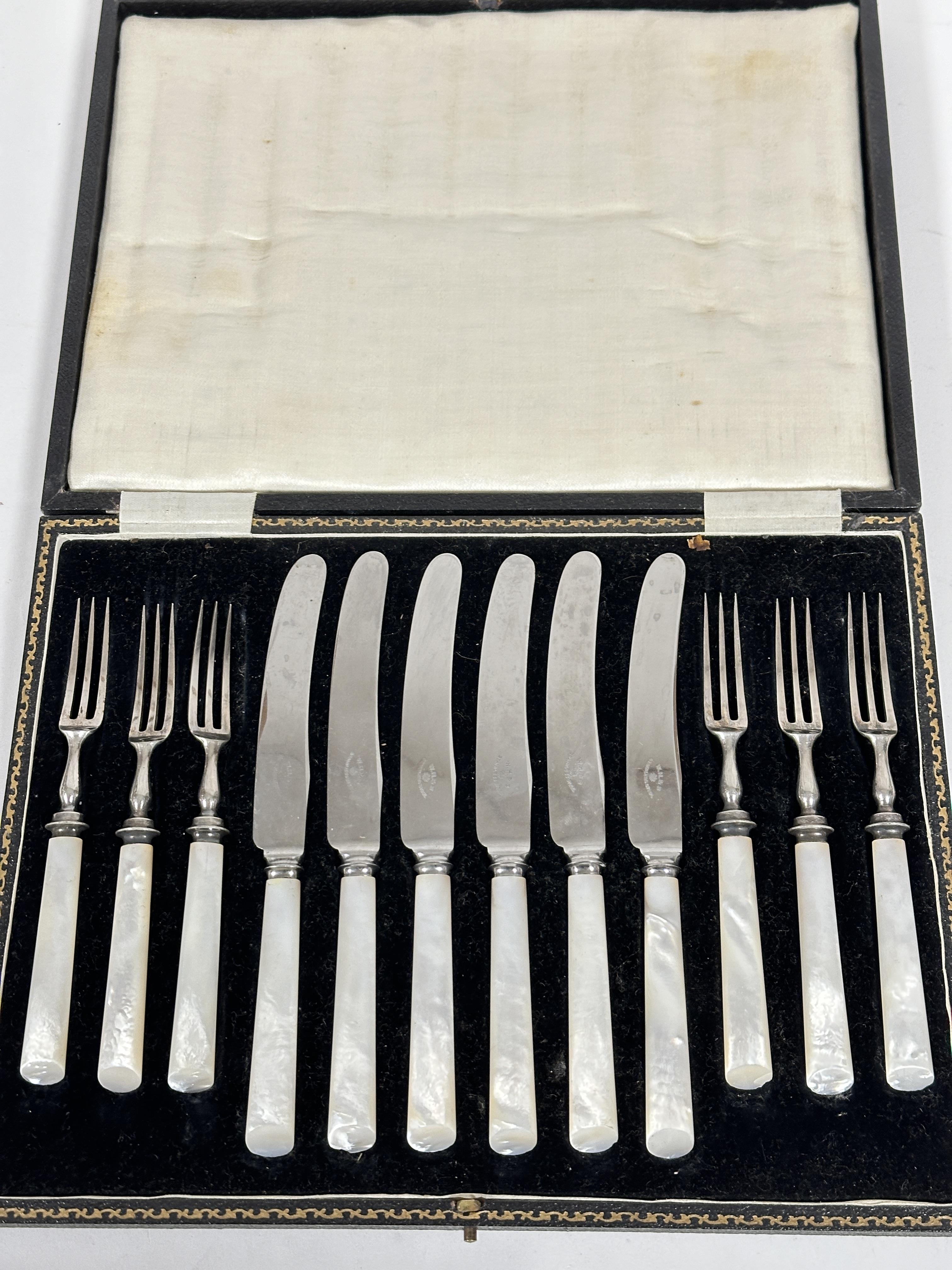 A set of six pairs of stainless steel bladed mother of pearl handled fruit knives and forks in