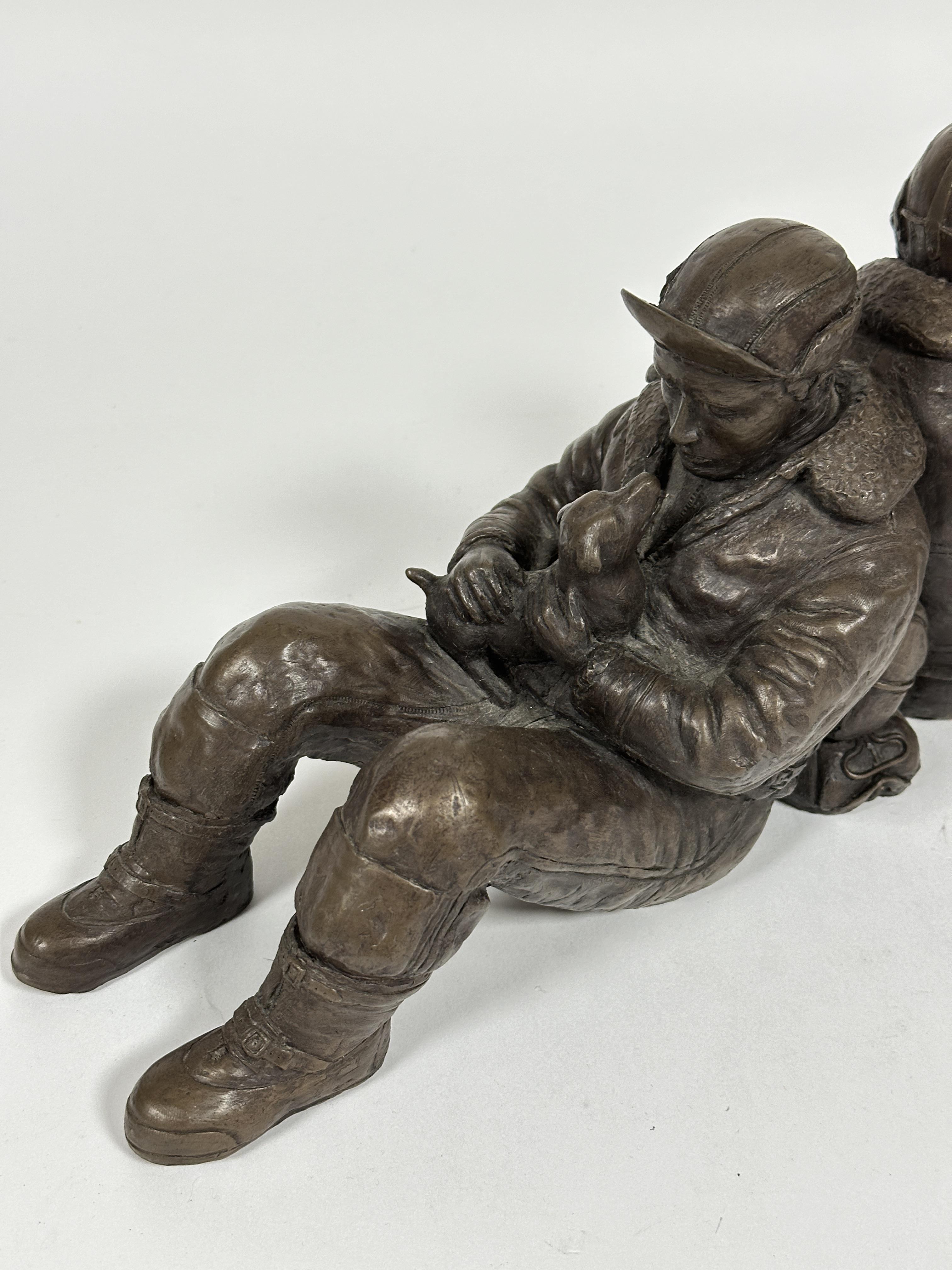 A modern cast resin group of WW II seated back to back airmen one with a dog, unmarked, (H x 17 cm x - Image 2 of 3