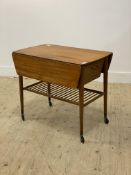 A mid century teak and teak veneered work table, the top with bowed ends and two drop leaves above a