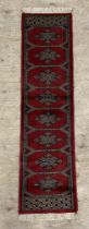 A red ground Bokhara runner rug with gul motif 125cm x 33cm