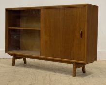 A mid century teak bookcase, fitted with two sliding doors enclosing shelves, raised on splayed