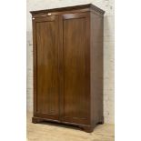 An Early 20th century mahogany wardrobe, the projecting cornice above two panelled doors enclosing a