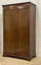 An Early 20th century mahogany wardrobe, the projecting cornice above two panelled doors enclosing a