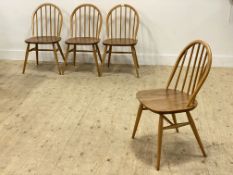 Ercol, a set of four beech and elm hoop and spindle back dining chairs, with saddle seats, raised on
