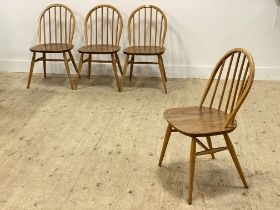 Ercol, a set of four beech and elm hoop and spindle back dining chairs, with saddle seats, raised on